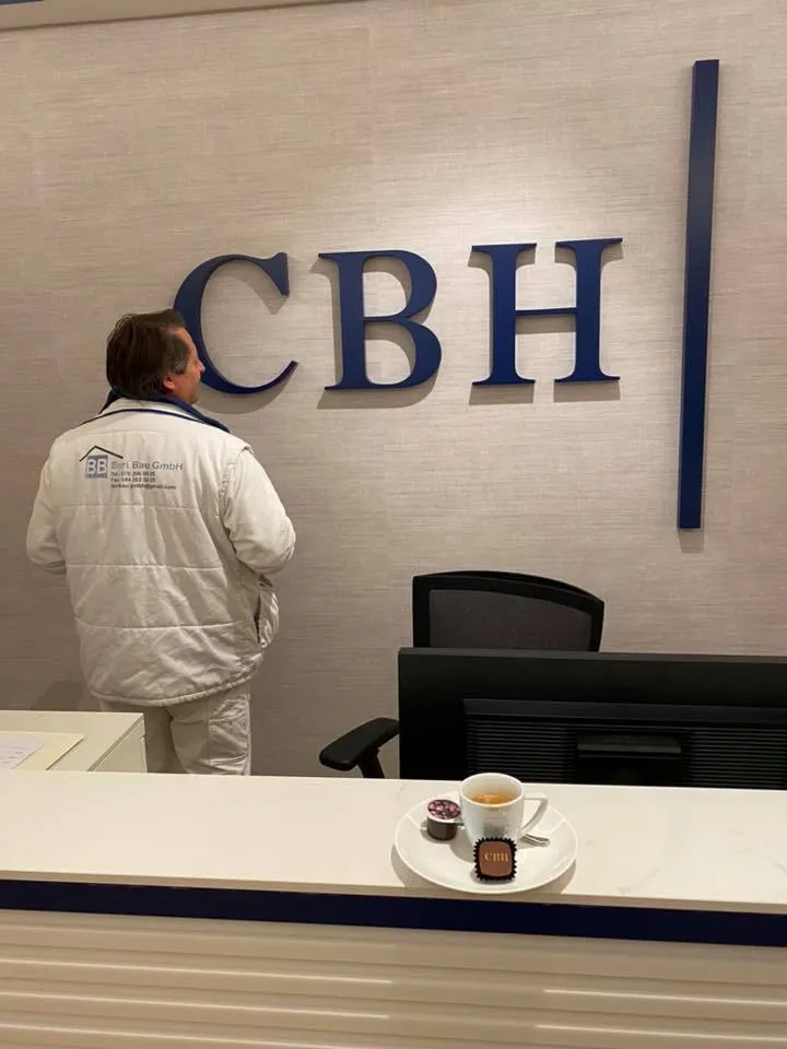 Empfangstheke vor der hell tapezierten Wand mit Firmenschriftzug.
