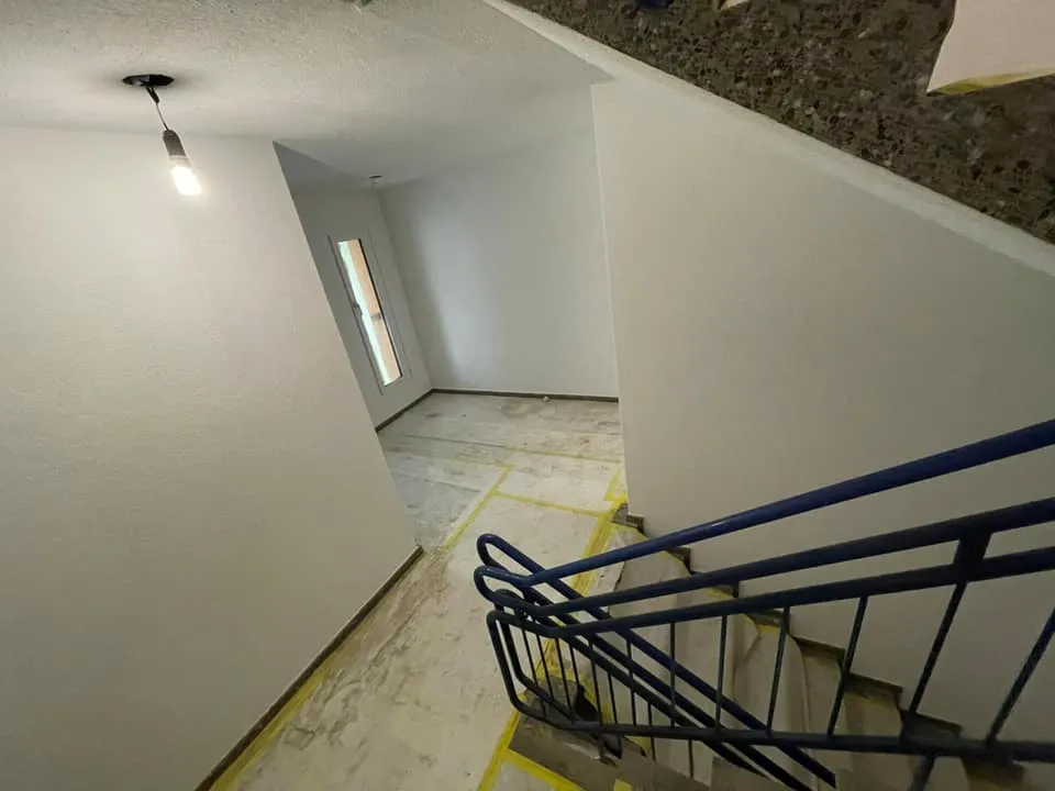 Treppenpodest mit neu gestrichenen Wänden und Bodenschutz.