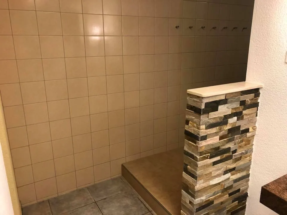 Neu geplattete Duschwand mit Kleiderhaken und Natursteinabtrennung.