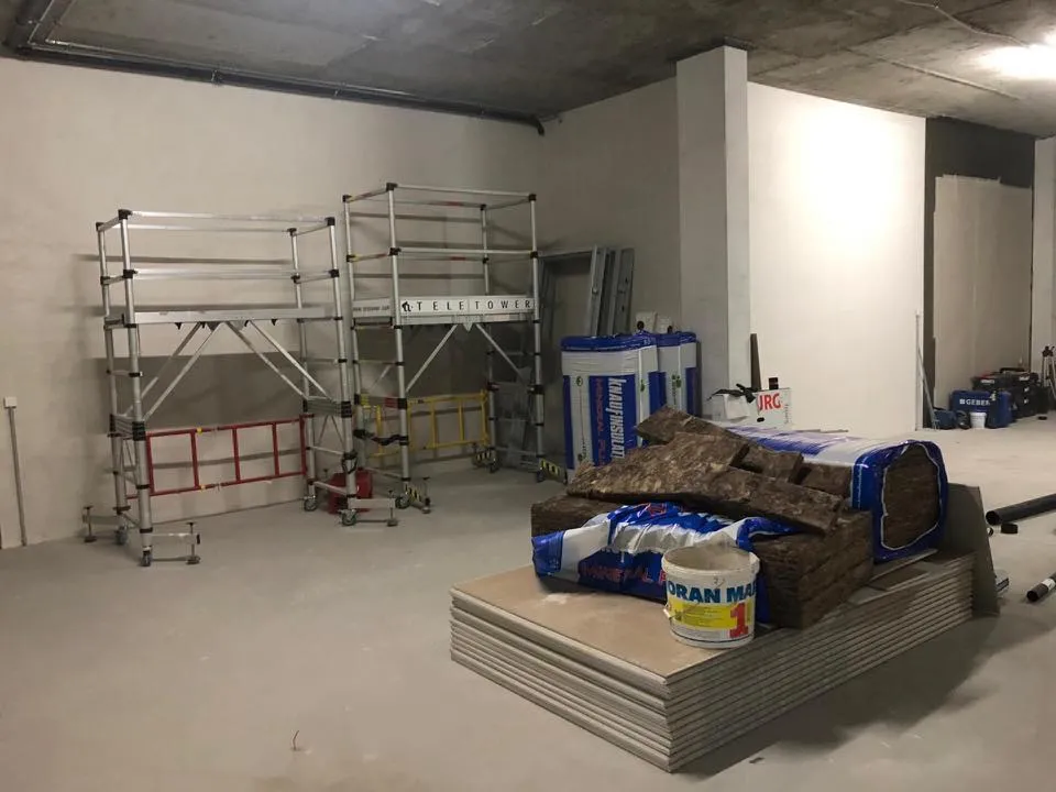 Rohbau mit Rollgerüsten, Gipsplatten und Dämmmaterial.