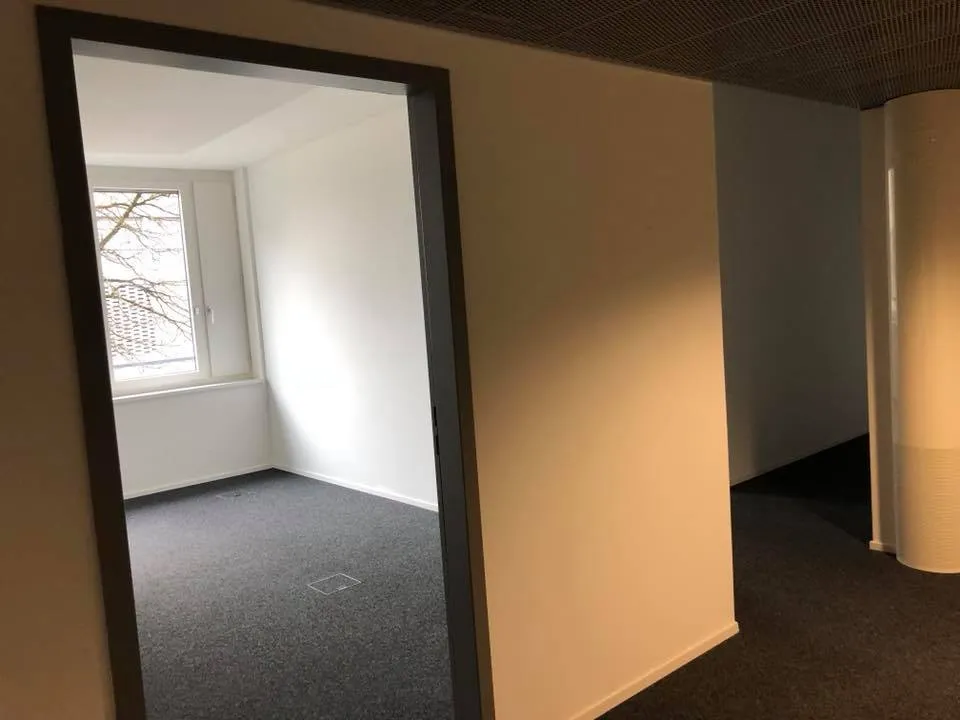 Blick durch eine Türöffnung in einen hellen Raum mit Fenster.