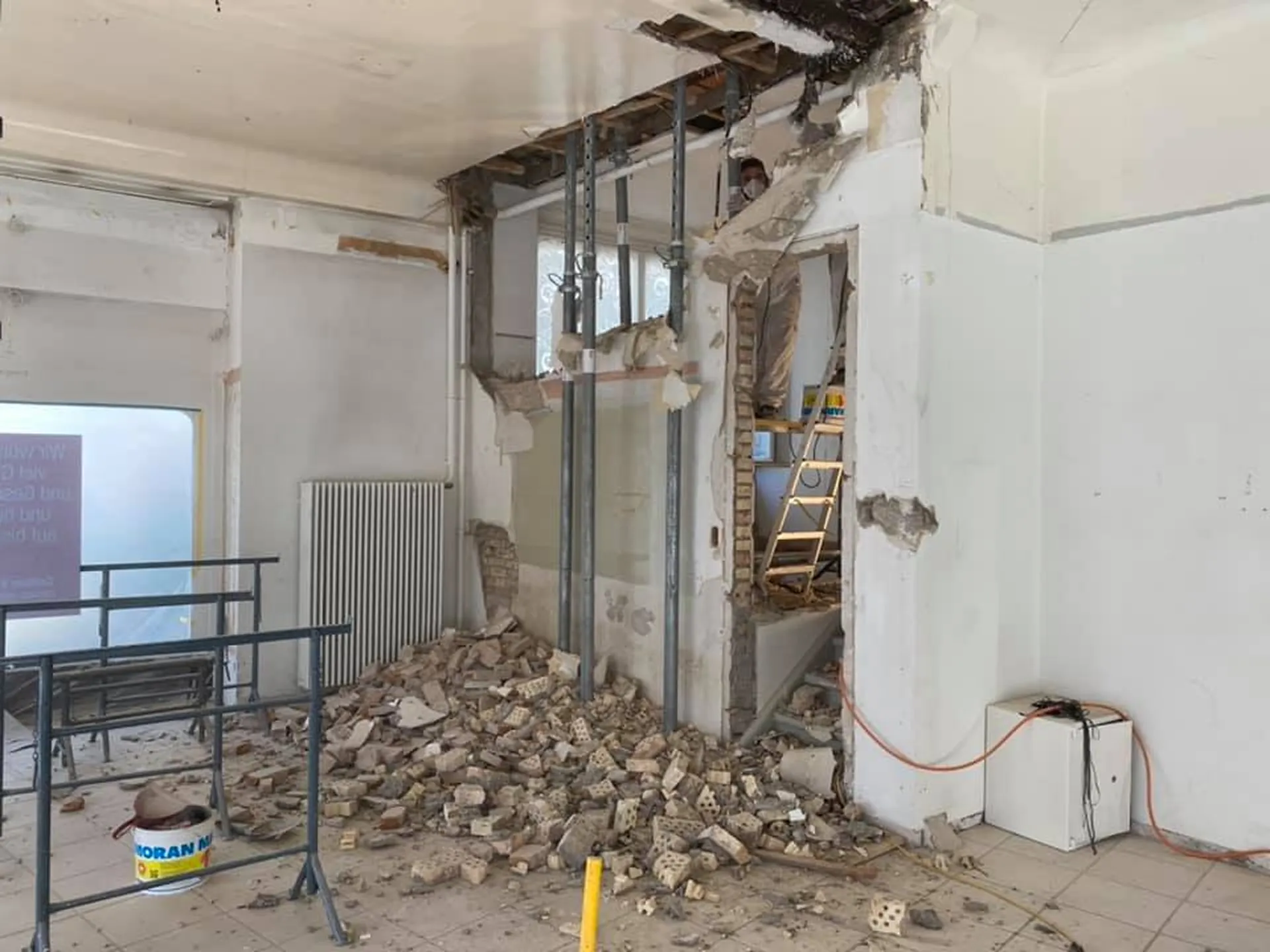 Abbruch einer Innenwand mit Schutt und provisorischen Stützen.