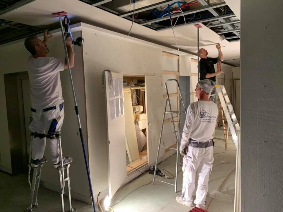 Handwerker bei Decken- und Wandarbeiten im teilweise offenen Rohbau.