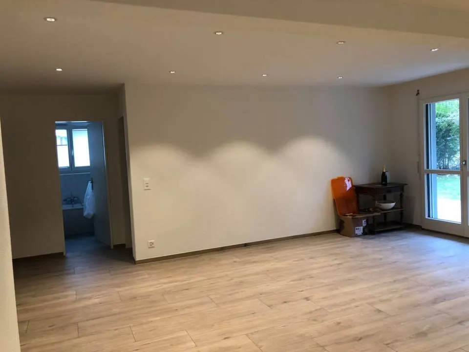 Heller Wohnraum mit Holzoptik-Boden und Zugang zum Garten.