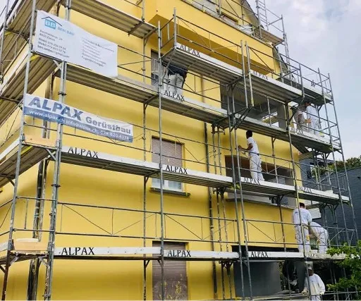 Maler auf dem Gerüst beim Beschichten der neuen Fassade.