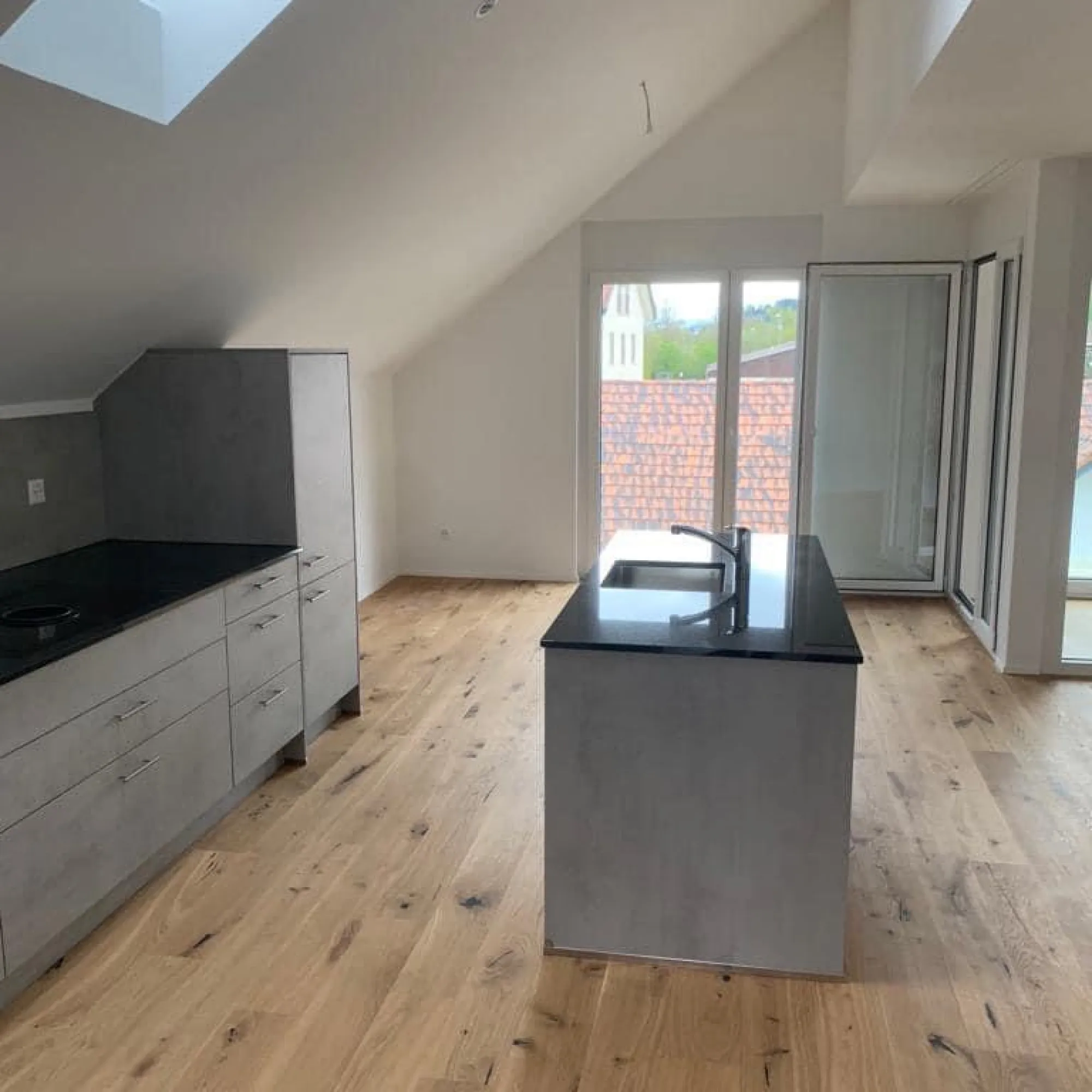Dachwohnung mit offener Küche, Kochinsel und neuem Holzboden.
