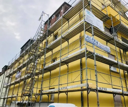 Vollständig eingerüstetes Mehrfamilienhaus mit neuem Fassadenanstrich.
