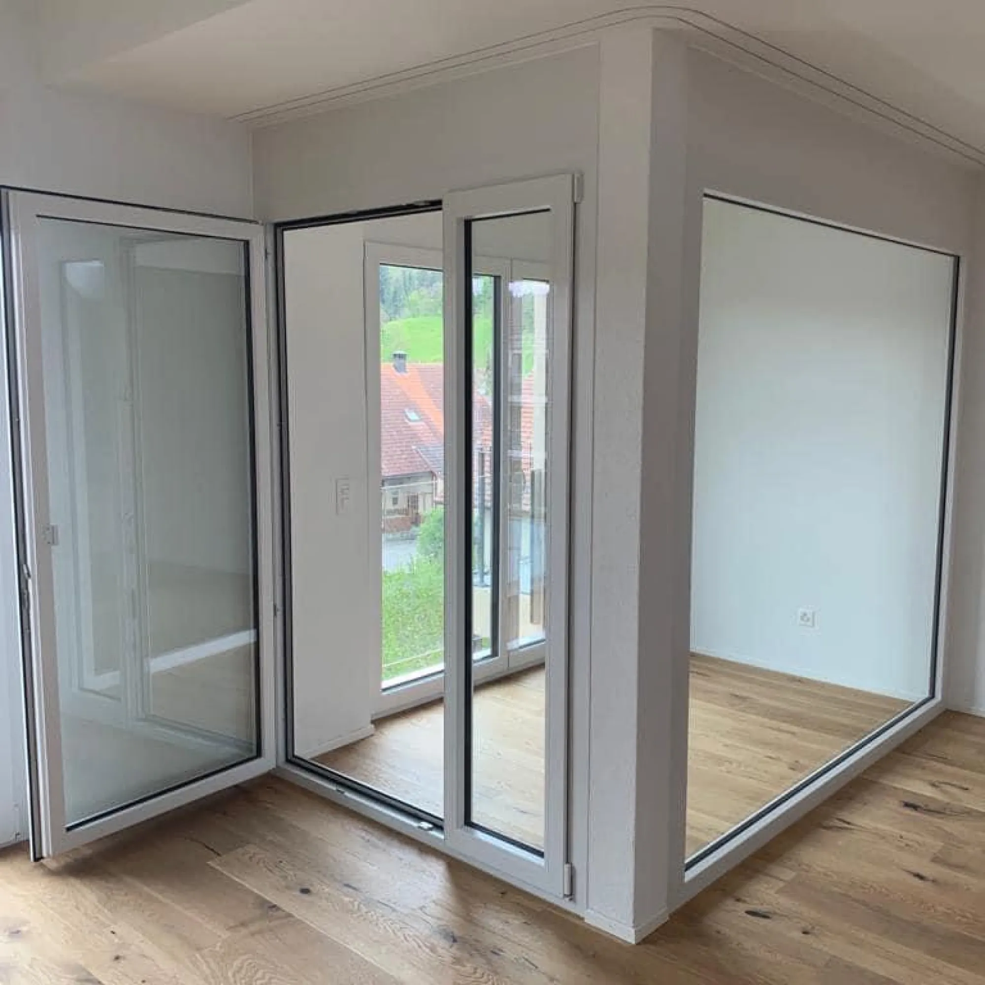 Heller Raum im Dachgeschoss mit Parkett und grossen Fenstertüren.