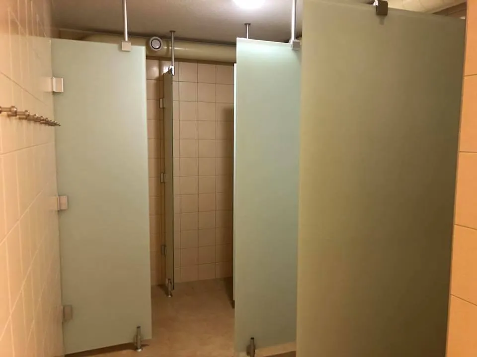 Duschkabinen mit satinierten Glastrennwänden im sanierten Duschraum.