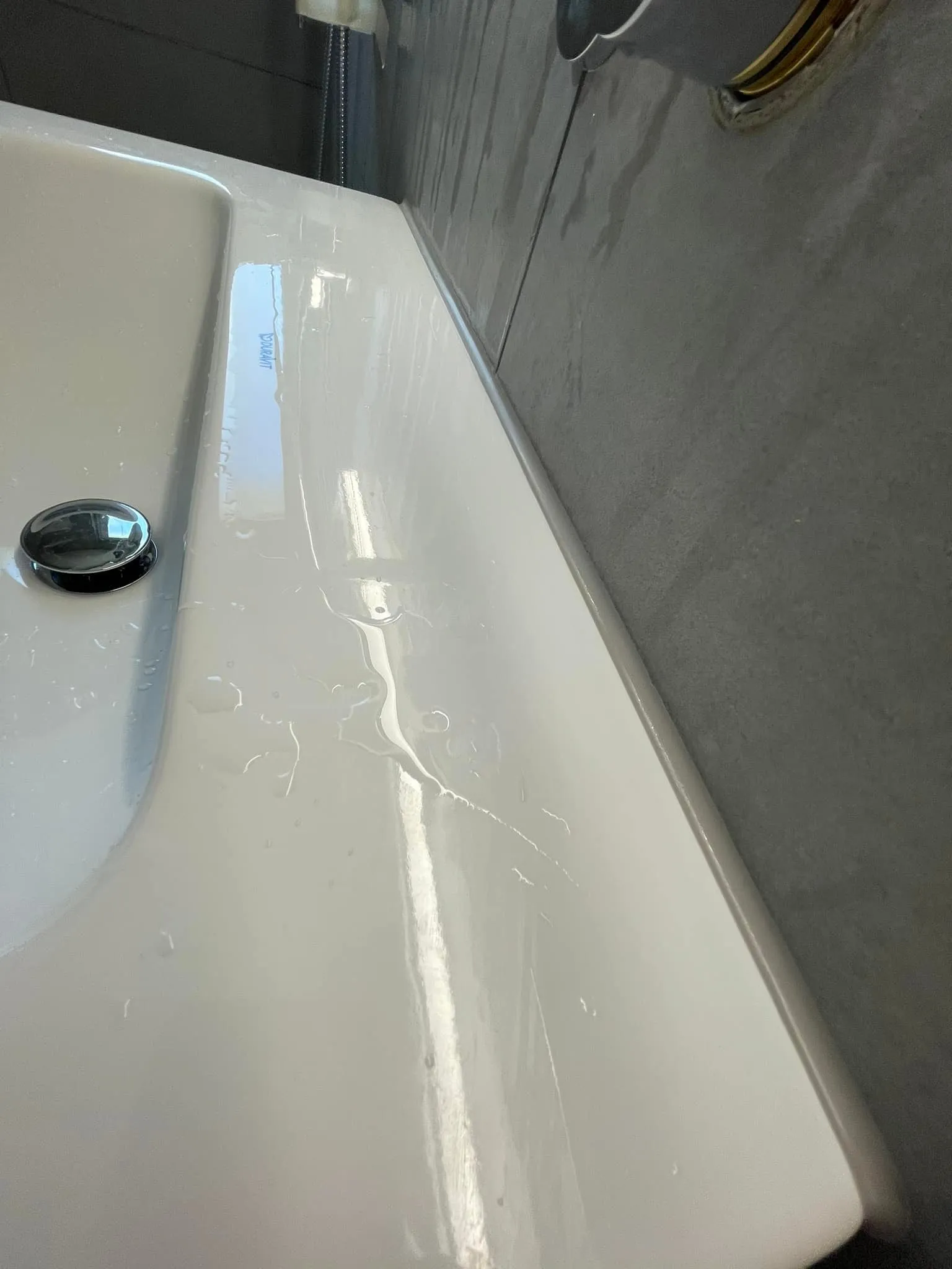 Nahaufnahme eines neuen Waschtischs vor der grau geplatteten Wand.