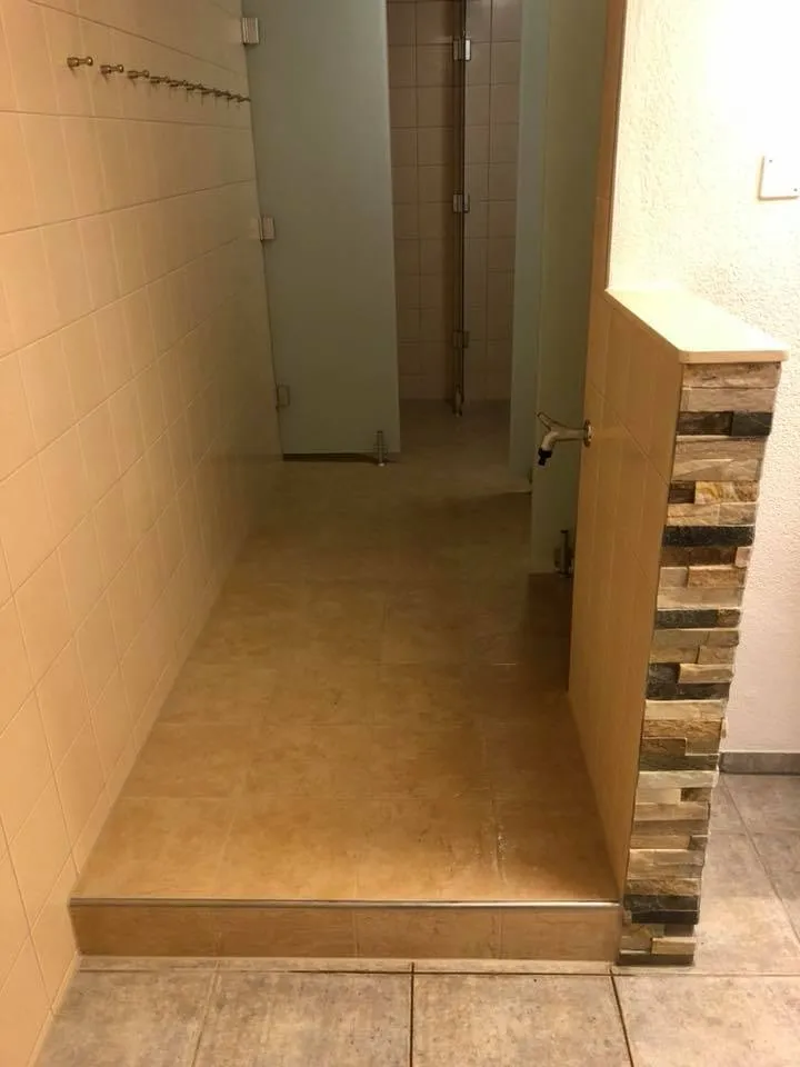 Aufgang zum Duschbereich mit Natursteinwand und neuem Plattenbelag.