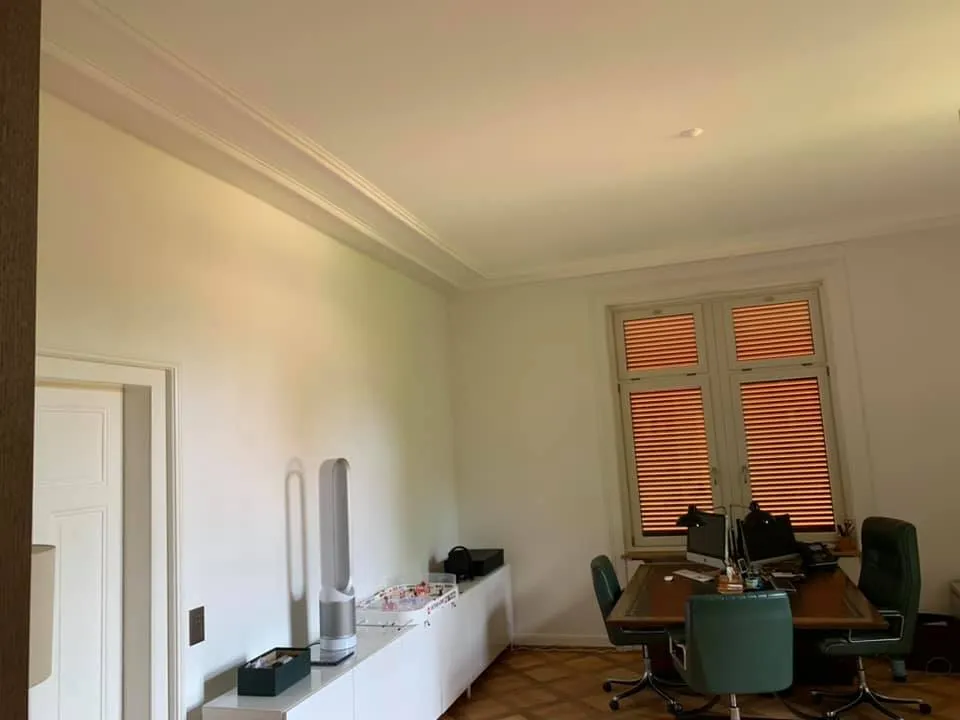 Arbeitszimmer mit Deckenprofilen, frisch gestrichenen Wänden und Parkett.