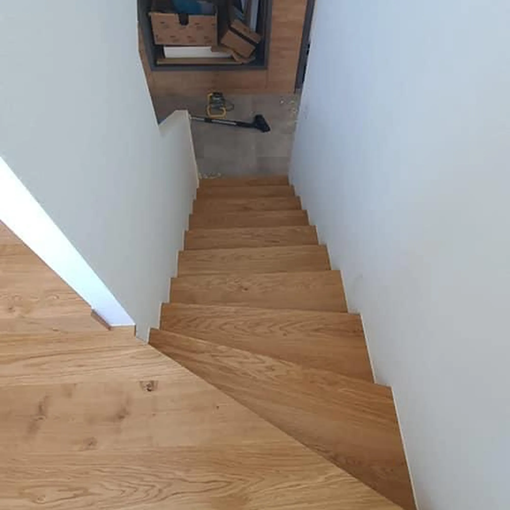 Treppe mit Eichenstufen und weiss gestrichenen Wänden.