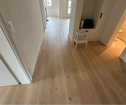 Korridor mit hellem Parkett in Landhausdielen und weissen Einbauten.