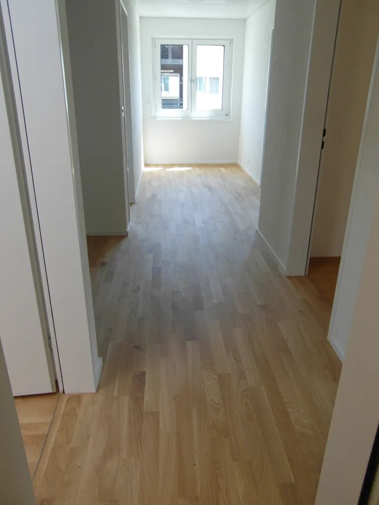 Korridor mit neuem Parkett und hell gestrichenen Wänden.