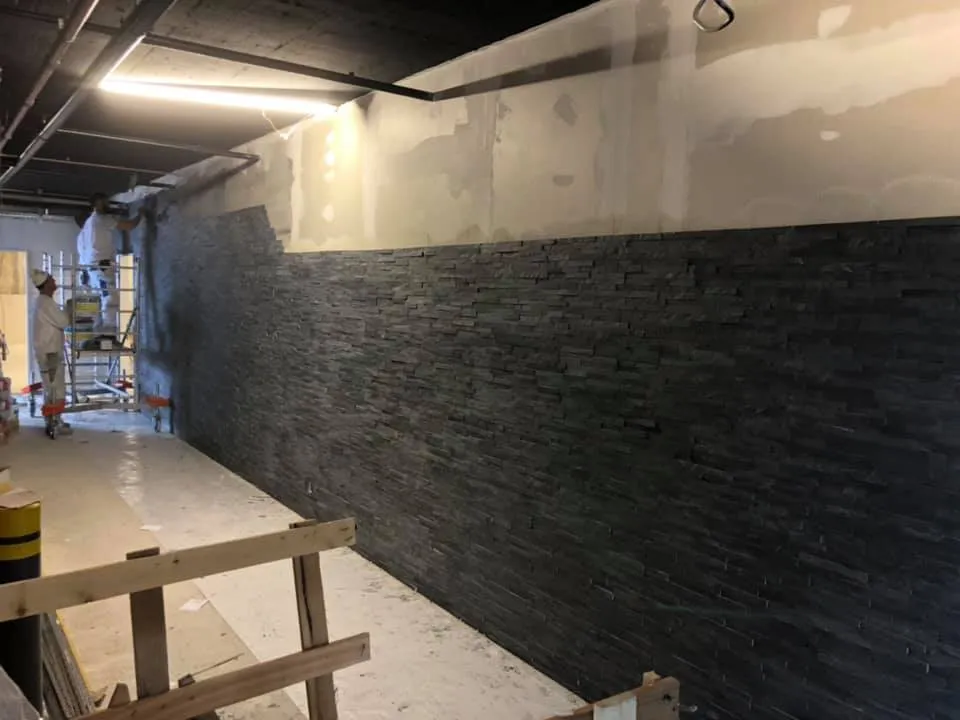 Korridorwand mit Natursteinriemchen bis auf halbe Höhe verlegt.