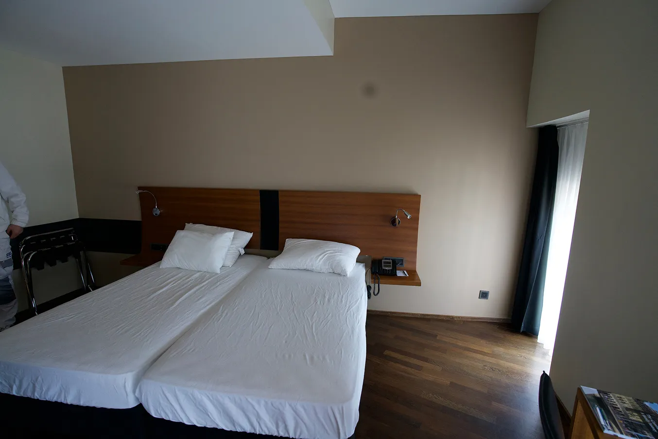Hotelzimmer mit Doppelbett, Holzboden und frisch gestrichenen Wänden.