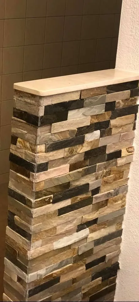 Nahaufnahme der Natursteinwand aus Riemchen mit heller Abdeckplatte.