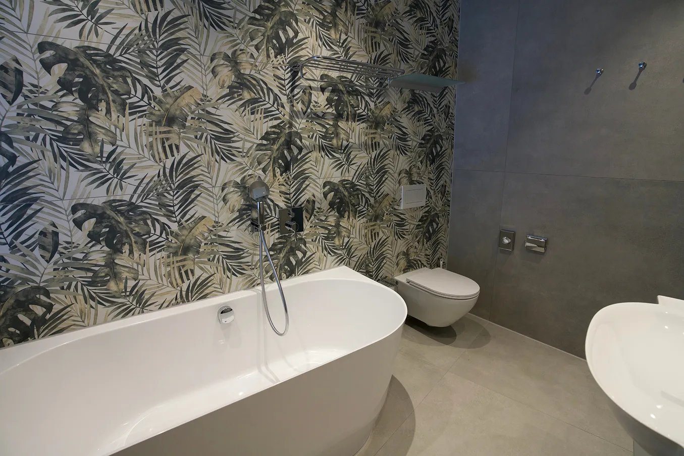 Bad mit freistehender Wanne vor dekorativer Blattmusterwand.