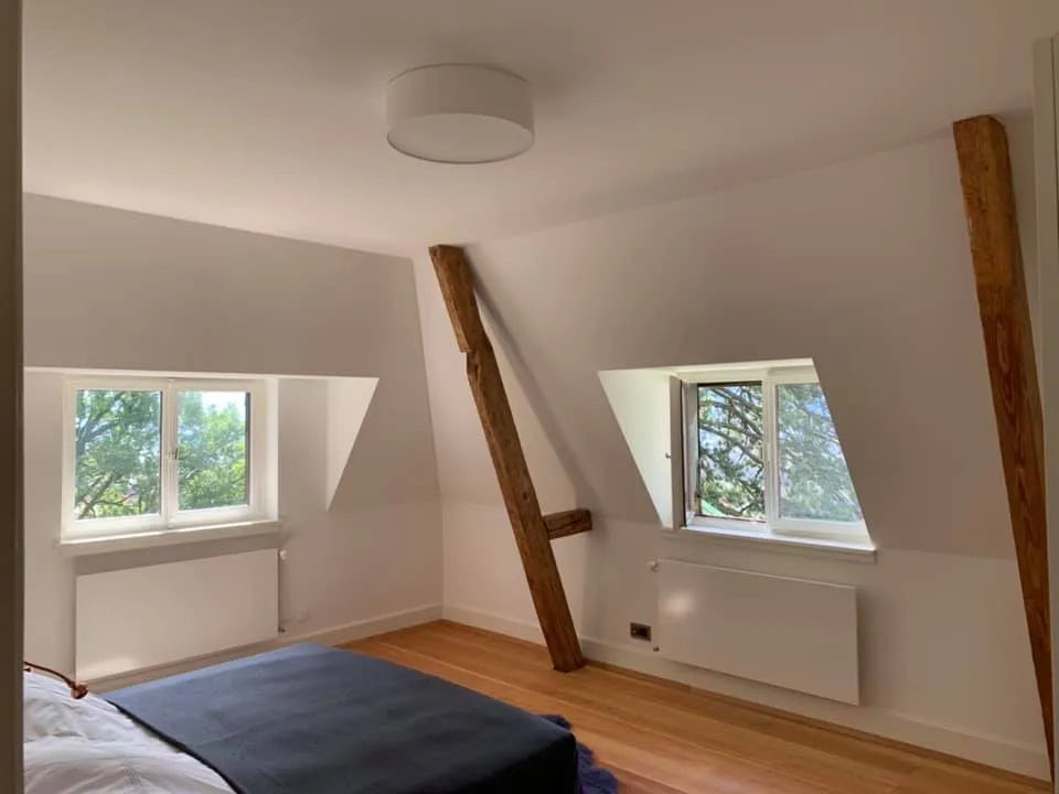 Schlafzimmer im Dachgeschoss mit sichtbaren Holzstreben und Parkettboden.