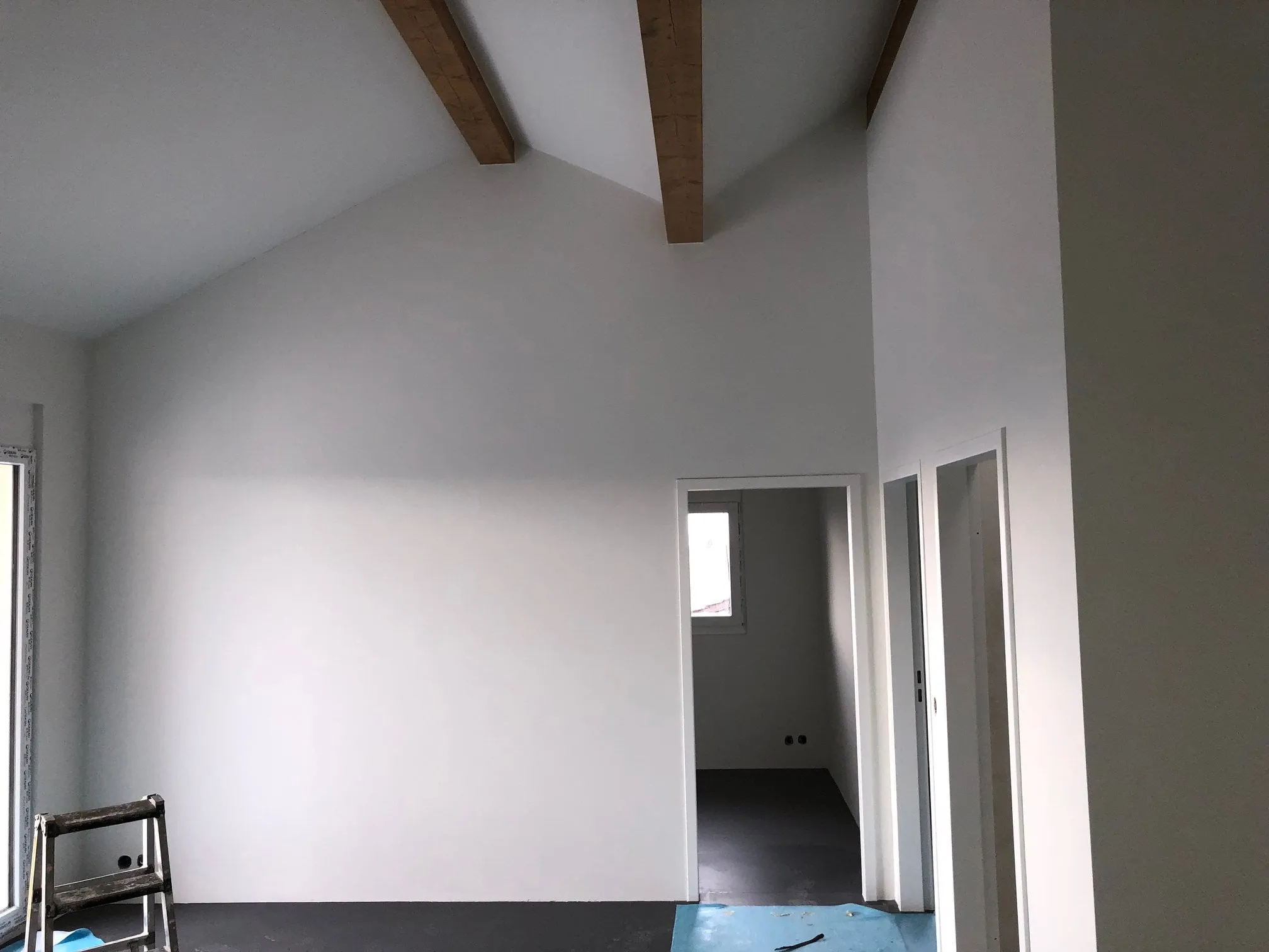 Heller Raum mit sichtbaren Holzbalken und frisch gestrichenen Wänden.