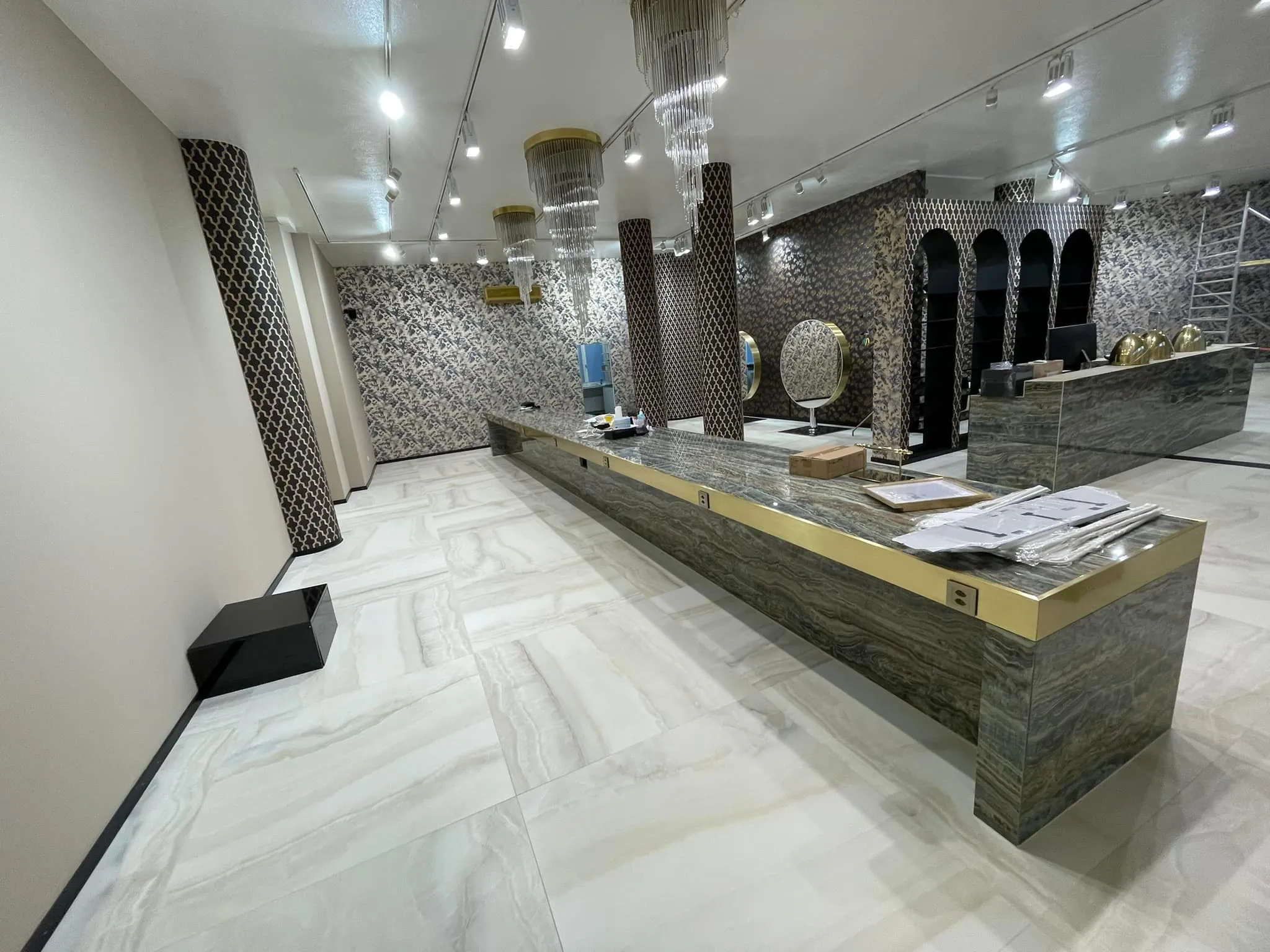 Salon mit langer Theke, Kristallleuchtern und Schienenspots.