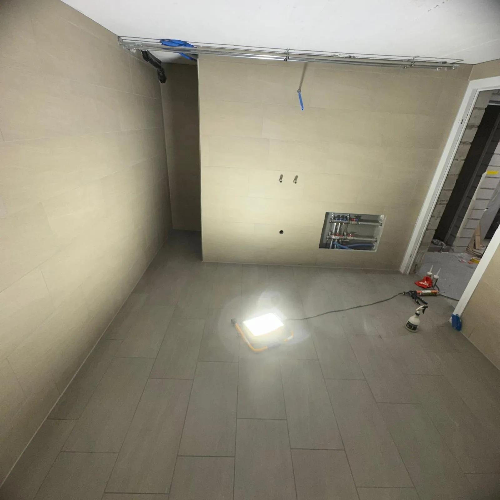 Raum mit fertig verlegten Wand- und Bodenplatten und Verteilerkasten.