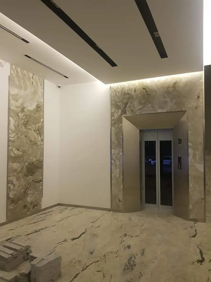 Eingangshalle mit Natursteinoptik an Wand und Boden vor dem Lift.