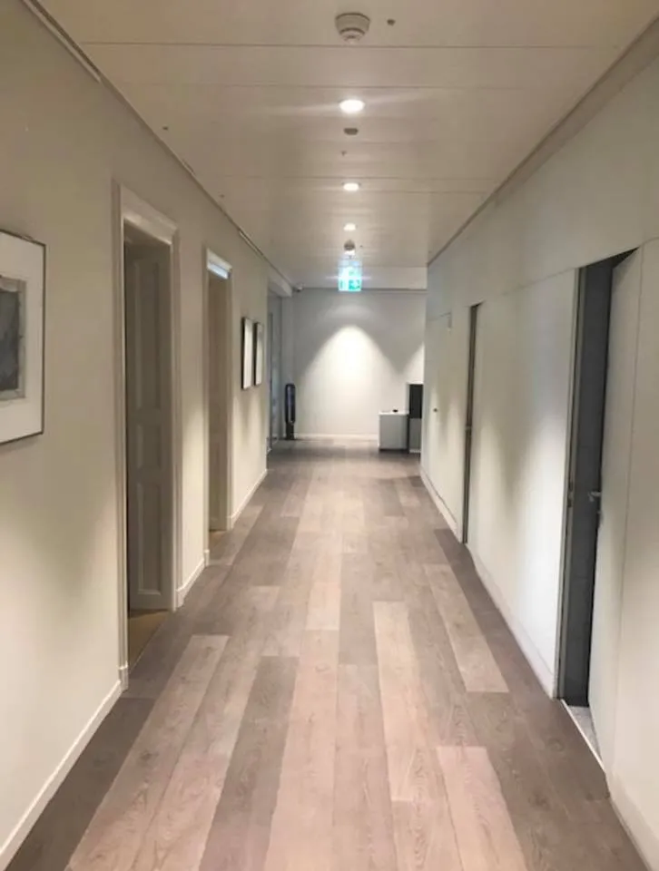Heller Bürokorridor mit Holzboden und Deckenspots.