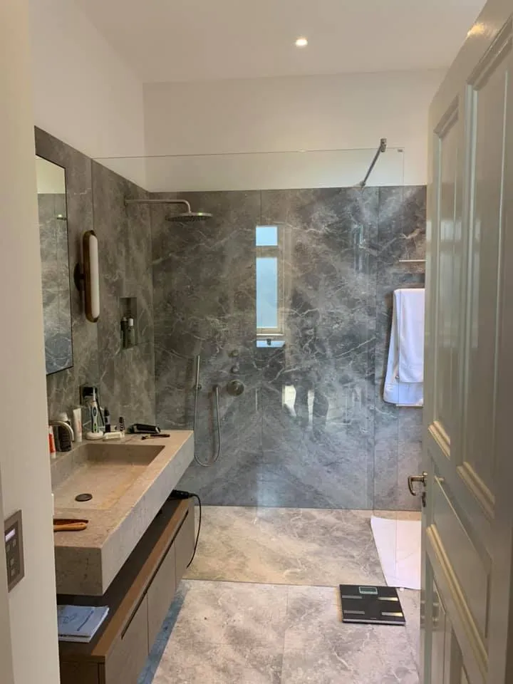 Badezimmer mit bodenebener Dusche und grossformatigen Platten in Marmoroptik.