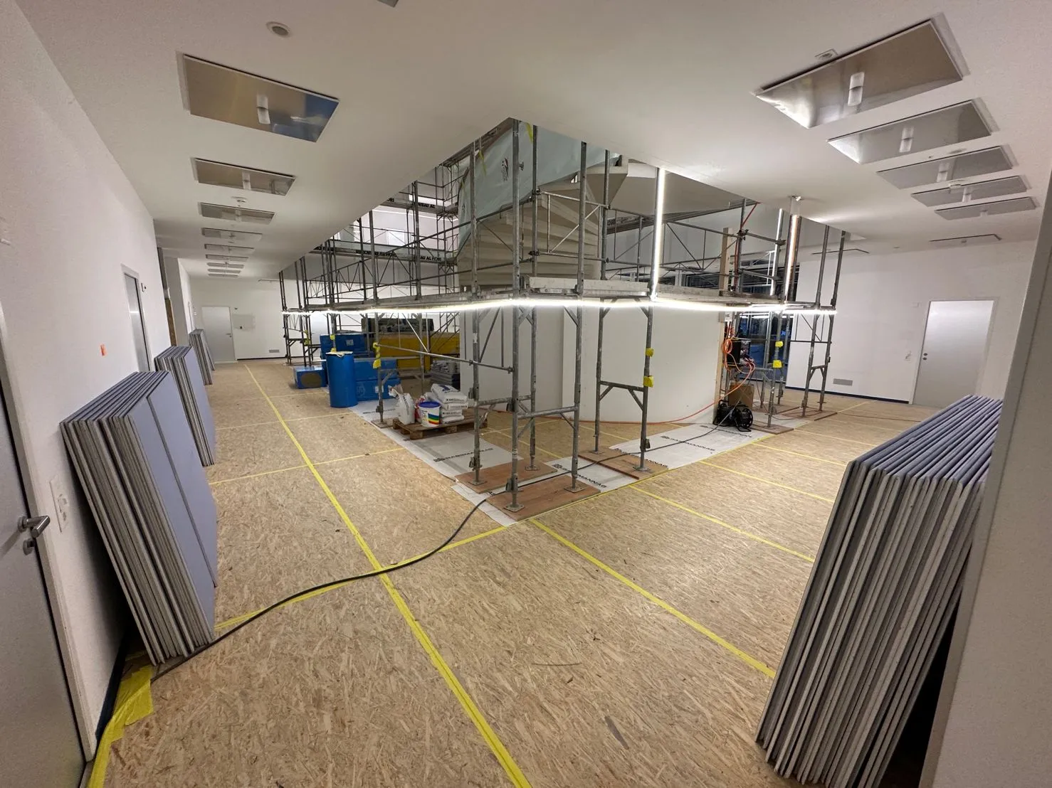 Innenausbau in Arbeit: Gerüst, Gipsplatten und abgeklebter Boden