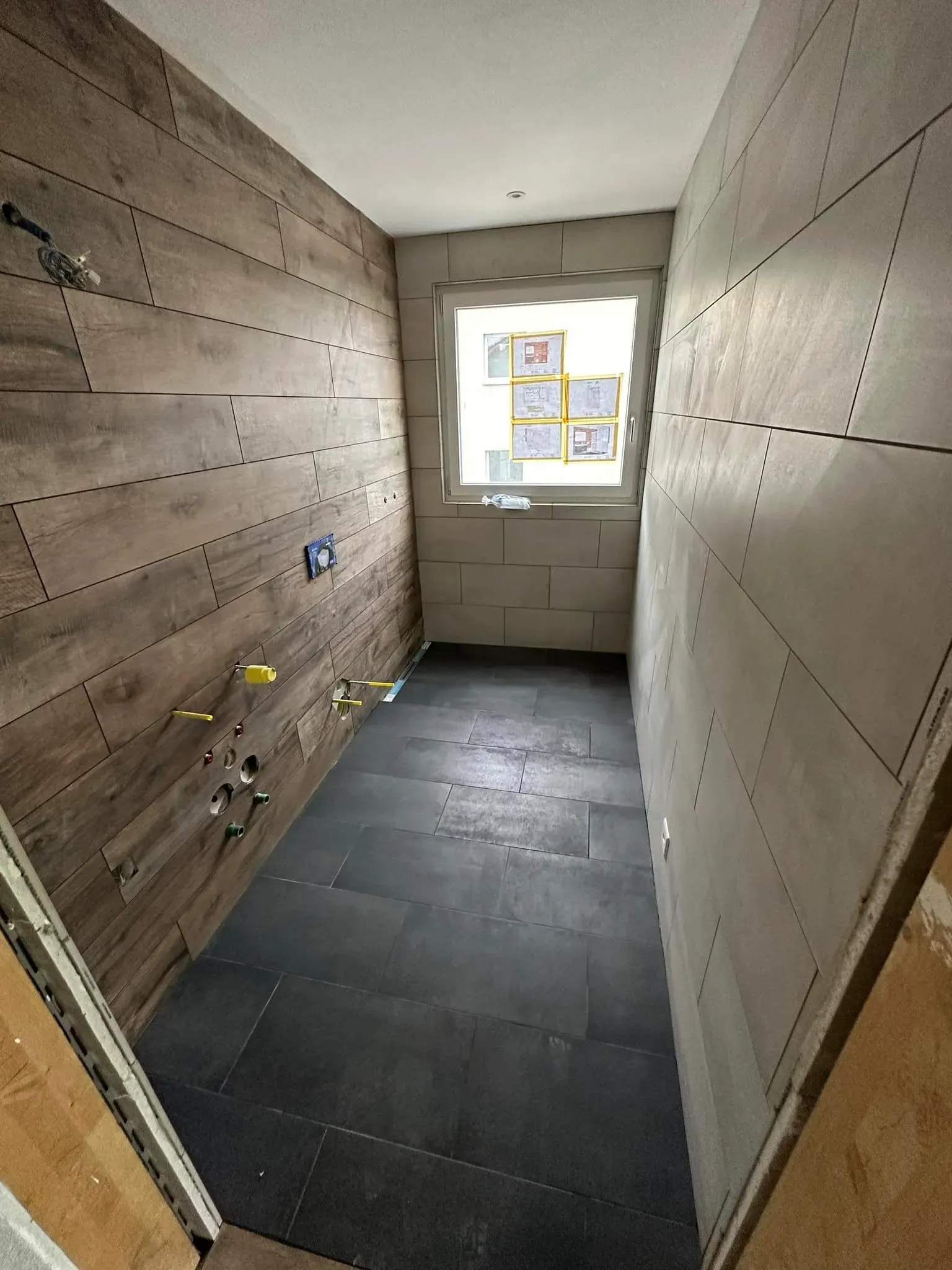 Bad im Ausbau mit neu verlegten Wand- und Bodenplatten